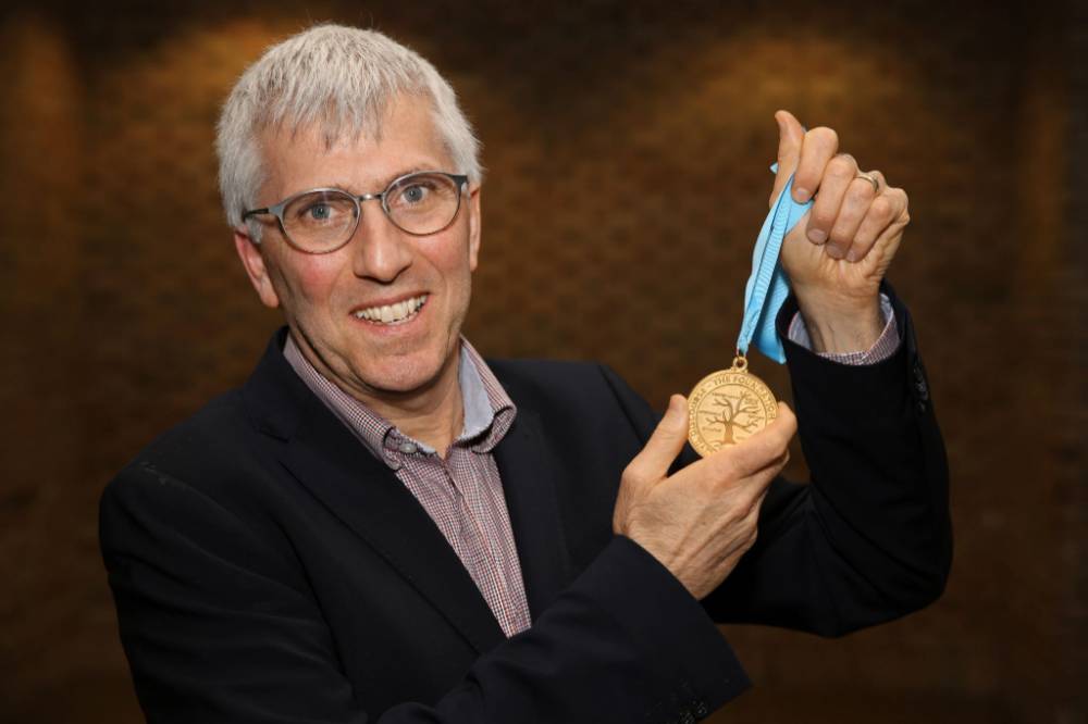 Jeff Kelly Lowenstein, the fourth endowed professor of civil discourse, poses with his medallion